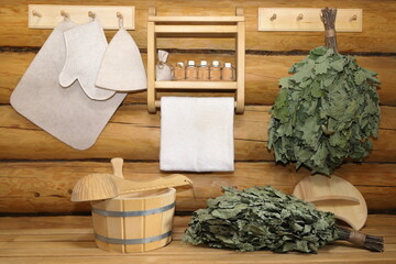 Traditional sauna accessories and oak brooms are in interior of log bath house.  - obrazy, fototapety, plakaty