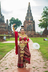 Obraz premium Portrait Asian woman in a red Thai dress posting with An old Buddhist temple at Wat Chai wattanara at Ayutthaya