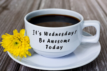 Text on white coffee cup with yellow flower on wooden desk. Wednesday concept.