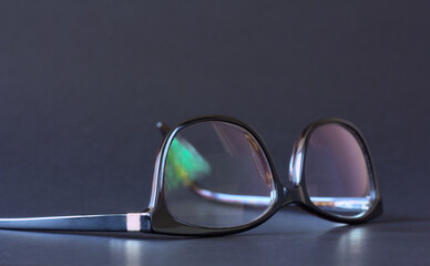 Anti-glare coating on the glasses. Glasses with black frames on a dark background.