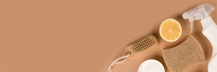 Banner with organic household cleaners kit - bamboo brush, organic dishcloth, lemon, baking soda, citric acid, spray bottle with cleaning liquid on beige background with copy space