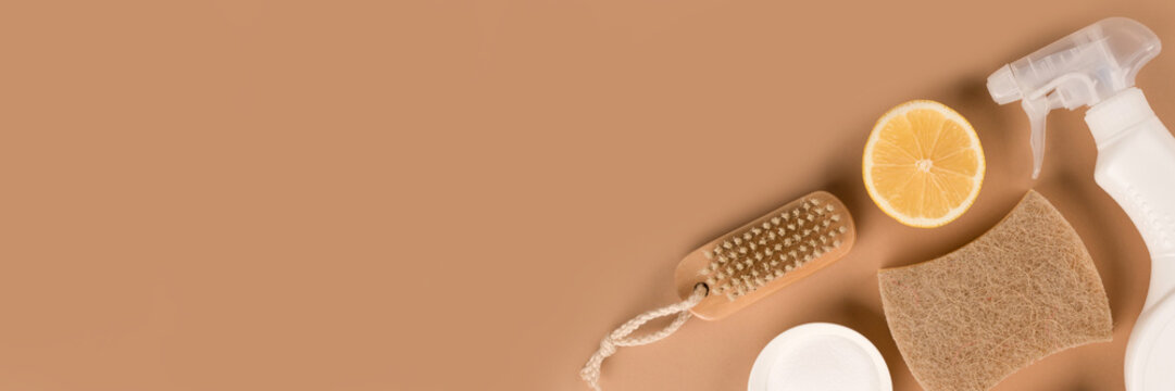 Banner with organic household cleaners kit - bamboo brush, organic dishcloth, lemon, baking soda, citric acid, spray bottle with cleaning liquid on beige background with copy space