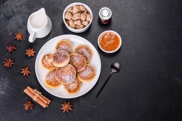 Cottage cheese pancakes with oats, syrniki on a black rustic background