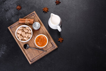 Obraz na płótnie Canvas Delicious apricot jam, milk and sugar on a wooden cutting board