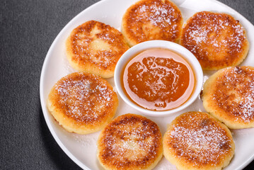 Cottage cheese pancakes with oats, syrniki on a black rustic background