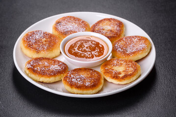 Cottage cheese pancakes with oats, syrniki on a black rustic background