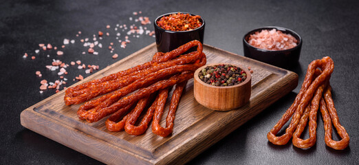 Smoked hunting sausages on a black stone background. Top view. Free copy space