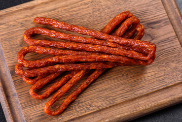 Smoked hunting sausages on a black stone background. Top view. Free copy space