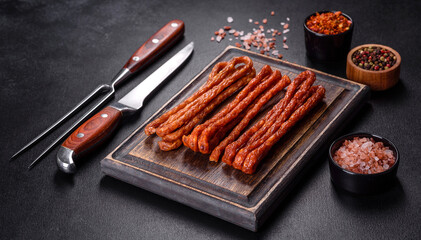 Smoked hunting sausages on a black stone background. Top view. Free copy space