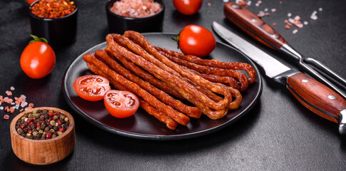 Smoked hunting sausages on a black stone background. Top view. Free copy space