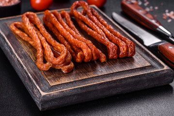 Smoked hunting sausages on a black stone background. Top view. Free copy space