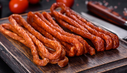 Smoked hunting sausages on a black stone background. Top view. Free copy space