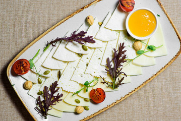 Various types of cheese with tomato, arugula, nuts on a plate. Restaurant menu. top view