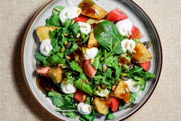 Warm tomato salad with baked vegetables, potatoes, close-up. top view