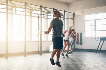 Perfecting his form. Shot of a muscular young man training with a skipping rope at the gym.