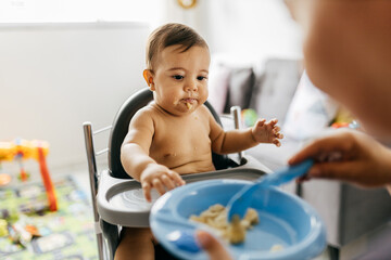 Mother feeding child. First solid food for children. Baby weaning