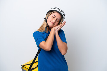 Young caucasian woman with thermal backpack isolated on white background making sleep gesture in dorable expression