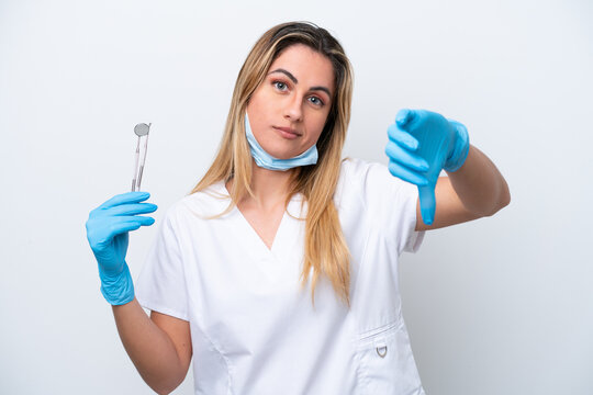 Dentist woman holding tools isolated on white background showing thumb down with negative expression