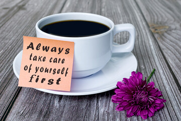 Motivational quote written on stick note with white coffee cup and purple flower