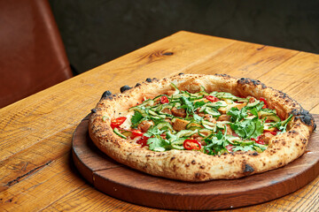 Vegetarian pizza with tofu and vegetables on a wooden board on a wooden background. Close up, selective focus