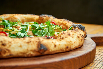 Vegetarian pizza with tofu and vegetables on a wooden board on a wooden background. Close up, selective focus