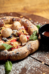 Small pizza with fruit and ice cream on a wooden board on a wooden background. Selective focus