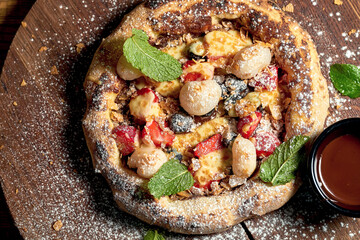 Small pizza with fruit and ice cream on a wooden board on a wooden background. Selective focus