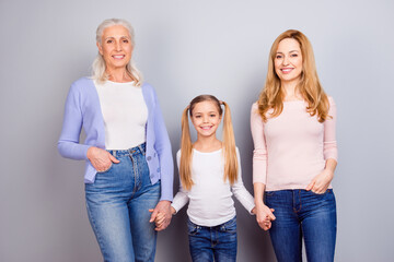Portrait of three idyllic peaceful people hold arms look camera isolated on grey color background