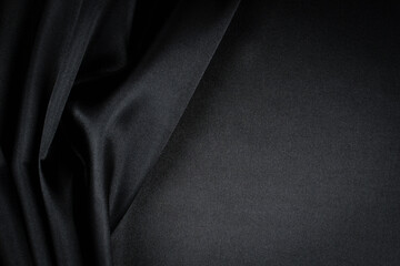 Beautiful background luxury cloth with drapery and wavy folds of black silk satin material texture....