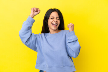 Young caucasian woman isolated on yellow background celebrating a victory