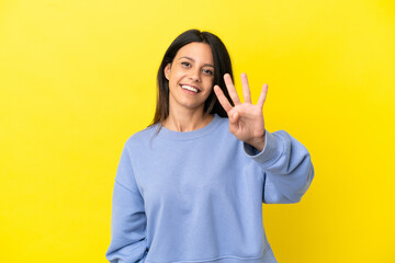 Young caucasian woman isolated on yellow background happy and counting four with fingers
