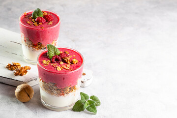 Yogurt, raspberry smoothie and homemade granola in a transparent glass. Healthy breakfast or snack. Copy space