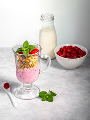Raspberry smoothie and homemade granola in a transparent glass. Healthy breakfast or snack. Copy space