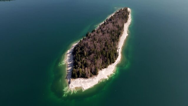 Aerial drone of Island of Sassau in Lake Walchen, Walchensee in Bavaria Germany, with Herzogstand mountain in spring in 4k, HD und UHD