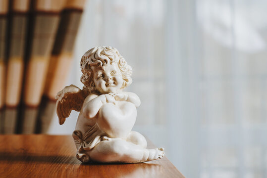 beautiful ceramic figurine of an angel on the table on the background of the hotel room