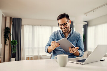 A man using technologies and holding tablet while sitting at home.