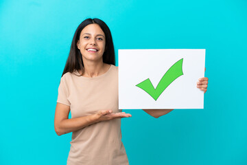 Young woman over isolated background holding a placard with text Green check mark icon and ...