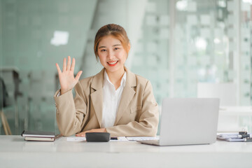 Portraits of beautiful smiling Asian women relax using laptop computer technology while sitting on their desks and using their creativity to work, work from home concept.