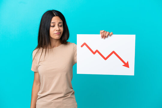 Young woman over isolated background holding a sign with a decreasing statistics arrow symbol with sad expression