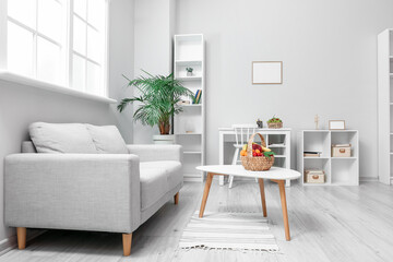 Interior of modern living room with grey sofa, table and fruit basket