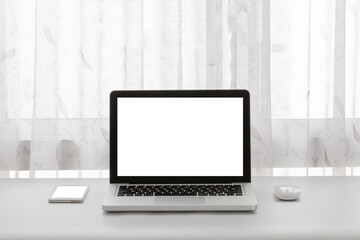 Laptop with mouse and smart phone on white table with curtain background