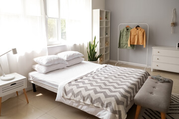 Interior of modern bedroom with rack and jackets