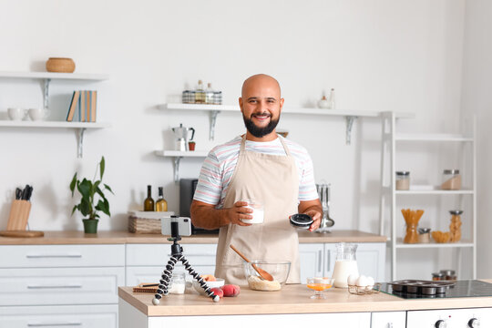 Handsome man making dough while following cooking video tutorial in kitchen