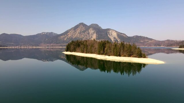 Aerial drone of Island of Sassau in Lake Walchen, Walchensee in Bavaria Germany, with Herzogstand mountain in spring in 4k, HD und UHD