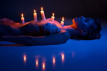 performance of laying sexy woman with burning candles on body - obrazy, fototapety, plakaty