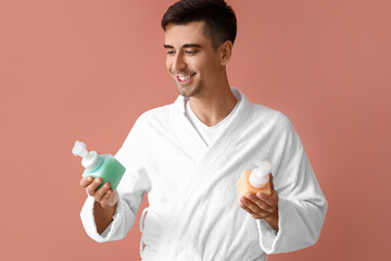 Handsome young man with different liquid soap on color background
