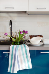 Bouquet of flowers purple tulips are watered in sink in kitchen