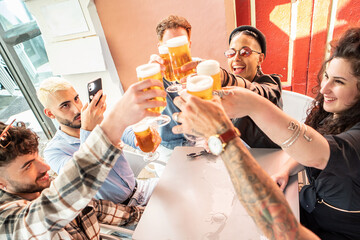 Group of friends drinking and toasting beer at brewery bar. Young millenial students having fun together.
