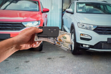 strong male hands holding dollar bills and car keys in the car.