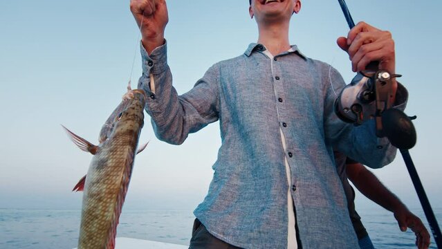 Amature angler holds the fish being on the boat in the open sea